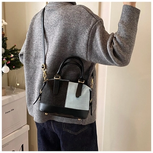 Detail of color-block Boston bag in blue denim and black leather with gold hardware
