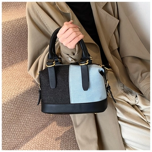 Detailed view of asymmetric denim patchwork texture and elegant gold hardware of handbag