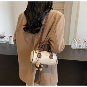 Detail of beige and brown cylinder crossbody bag styled with a khaki blazer