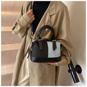 Detail of a color-block canvas Boston bag featuring leather handles and gold metal hardware