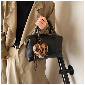 Détail du sac polochon en cuir noir avec breloque cœur léopard et logo doré gravé