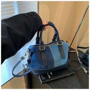 Detail of color-block denim Boston bag with leather trim and gold-tone hardware accents