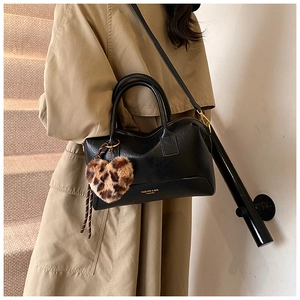 Détail du sac Boston noir avec pendentif cœur léopard et lettrage doré élégant