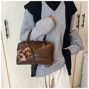 Détail du sac polochon marron vintage avec lettrage doré et breloque cœur léopard