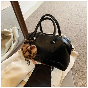 Détail du sac polochon noir avec breloque cœur léopard et fermeture éclair dorée