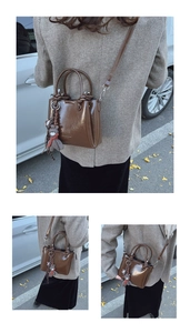 Détail d'un sac à main en cuir verni marron avec porte-clés ours et bandoulière fine