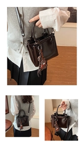 Détail du sac seau en cuir ciré marron foncé avec un petit ours et une bandoulière