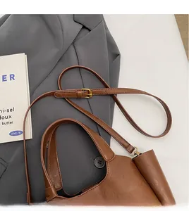 Détail de la bandoulière réglable en cuir marron avec boucle dorée sur un sac seau