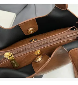 Détail d'un sac seau en cuir marron avec fermetures éclair et boucles magnétiques dorées