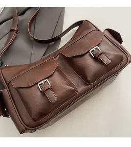 Detail view of brown faux leather shoulder bag with dual front pockets and silver buckles