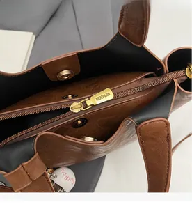 Détail du sac cabas bicolore en cuir avec fermeture éclair et pendentif baseball