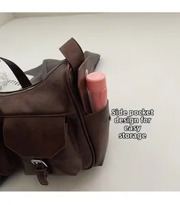 Detail of dark brown leather shoulder bag featuring a side pocket and front buckle pocket