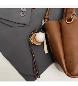 Détail d'un pendentif baseball avec gant et batte sur un sac seau en cuir marron