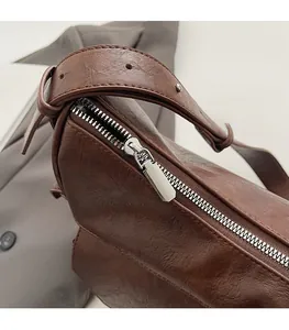 Close-up of smooth silver zipper and metal stud details on brown leather handbag