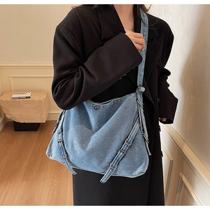 Detail of large denim hobo bag with silver metal rings and adjustable strap buckles