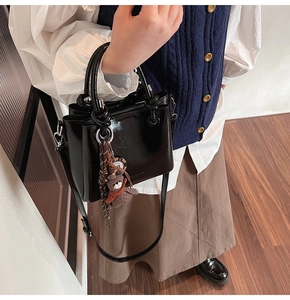 Detalle de bolso cubo negro brillante con colgante de oso y herrajes plateados fijos