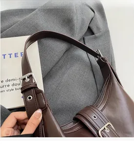 Dettaglio borsa in pelle marrone scuro con cerniera metallica e cinturino con fibbia