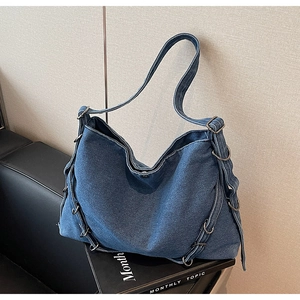 Macro detail of washed blue denim hobo bag featuring silver metal rings and straps