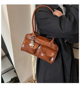 Brown patent leather tote bag with dual utility pockets and heart-shaped silver charm