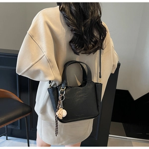 Sac seau noir minimaliste avec charm d'ours porté à l'épaule par un mannequin