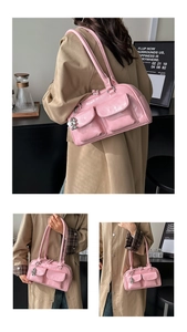 Detailed view of pink patent leather shoulder bag with dual front pockets and silver charm