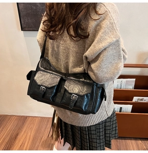 Detail of black faux leather shoulder bag with two front flap pockets and metal buckles