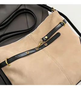 Detail of soft beige suede fabric and contrast black leather strap with gold buckle