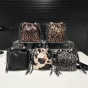 Stylish leopard and cow print bucket shoulder bag with black and white drawstring.