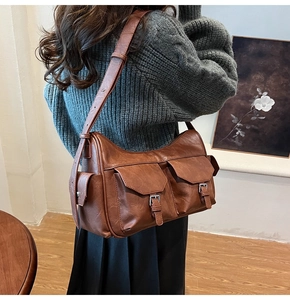 Detail view of a vintage brown multi-pocket crossbody bag worn by a model in interior