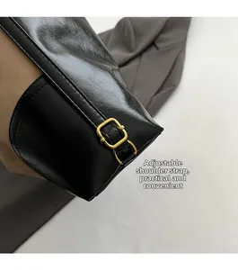 Detail of adjustable black leather shoulder strap with bronze metal buckle