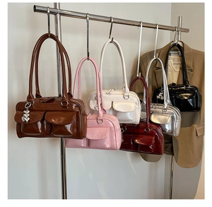 Close-up of shiny patent leather tote bags with dual front pockets and heart charms