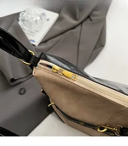 Detail of khaki suede and black leather bag showing smooth gold zipper and D-ring