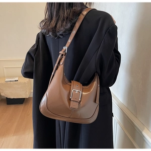 Borsa hobo in pelle marrone con fibbia in metallo e tracolla regolabile su modella