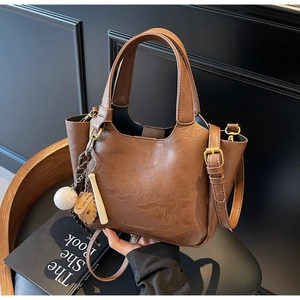 Détail du sac seau marron vintage avec texture litchi et breloques de baseball