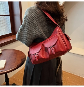 Detail view of red faux leather shoulder bag featuring multiple utility flap pockets