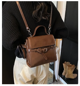 Detail of dark brown vintage oil leather backpack shown on model in a stylish indoor setting