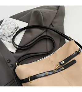 Detail of minimalist beige suede crossbody bag with gold hardware and smooth shoulder strap