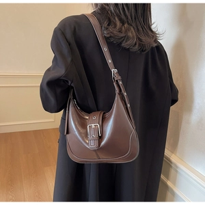 Borsa hobo in pelle marrone con occhielli metallici indossata da una modella alla moda