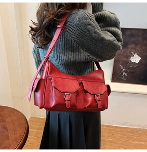 Close-up of red retro faux leather shoulder bag with multi-pocket and buckle detail