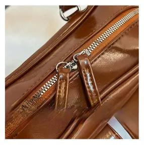 Detail of silver dual metal zippers on vintage brown glossy leather tote shoulder bag