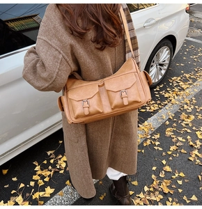 Detailed view of caramel leather shoulder bag featuring functional front pockets and metal buckles