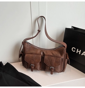 Detail view of brown vintage crossbody bag with dual front pockets and silver buckles