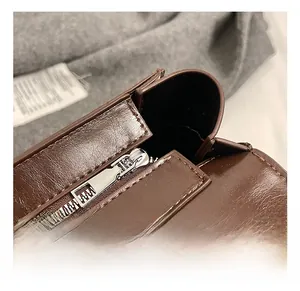 Close-up of premium silver metal zipper and reinforced stitching on brown leather bag