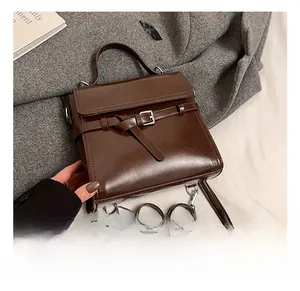 Close-up of brown vintage leather handbag showing metal buckle detail and top handle