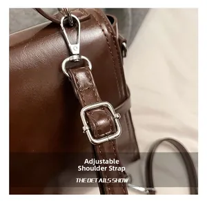 Detail of adjustable dark brown leather shoulder strap with polished silver metal buckle