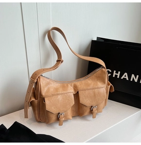 Macro shot of camel PU leather shoulder bag featuring dual buckle pockets and silver zippers