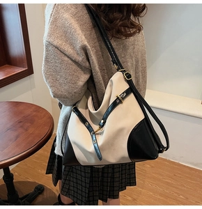 Detail of beige and black bucket bag with leather accents and gold buckle on side