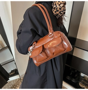 Detail of a brown glossy leather underarm bag with double pockets and heart charm