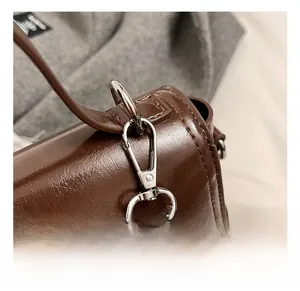 Detailed close-up of premium silver metal swivel hook and dark brown oil wax leather bag