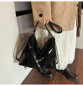 Detail of black nylon and leather tote bag with gold hardware held by a model